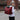 a woman wearing a white sweater carries a red backpack duffle bag across the street