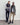 Two people wearing matching vests and sweaters standing against a plain background