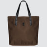 A brown nylon tote bag with black medium-length straps and a black patch with gold logo text
