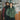 A man and a woman pose in a bagel shop, wearing sweaters and vests