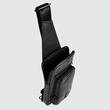 black leather sling bag, with top zip open to show the main interior, against a plain grey background